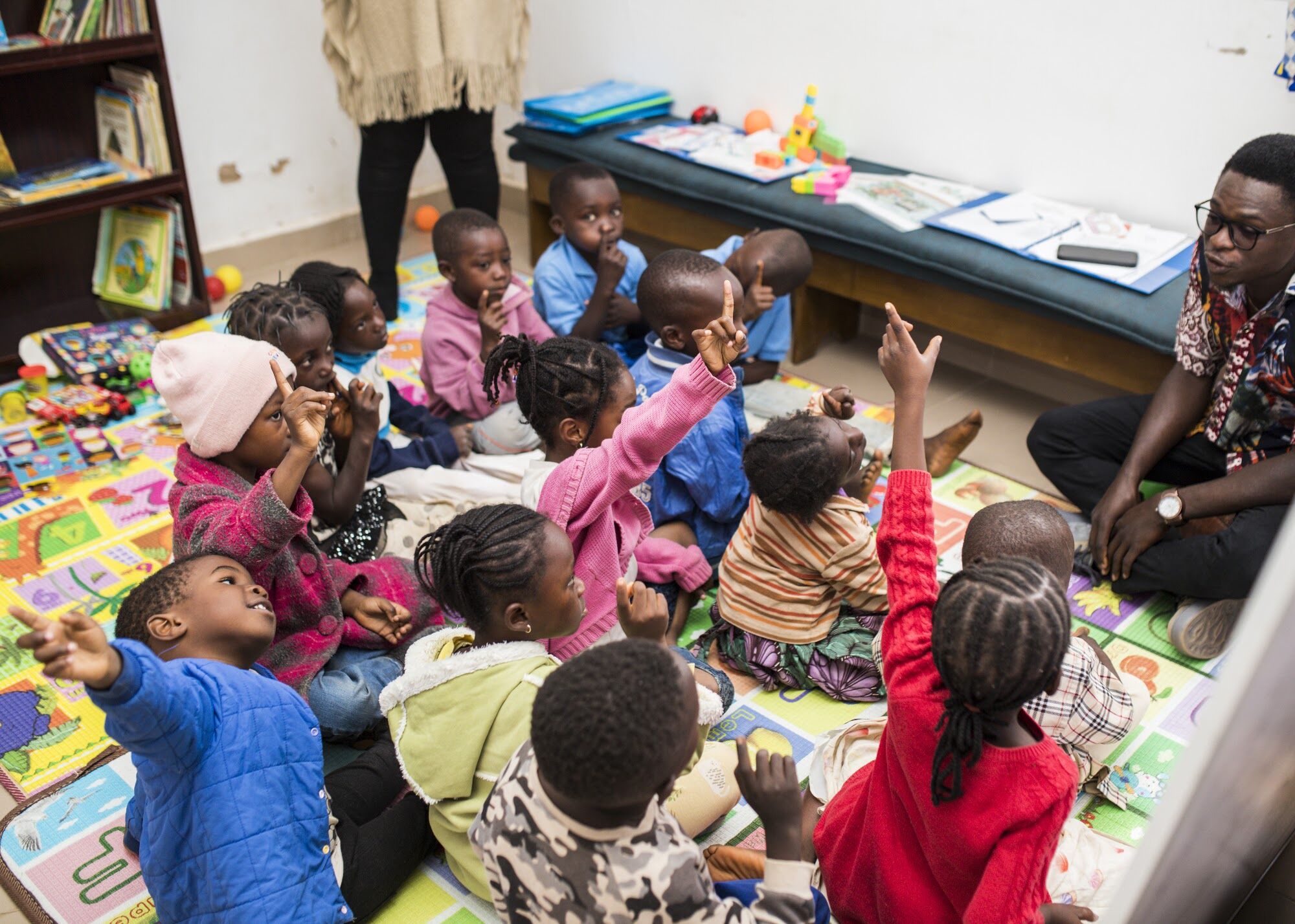 Young learners raising their hands during a class