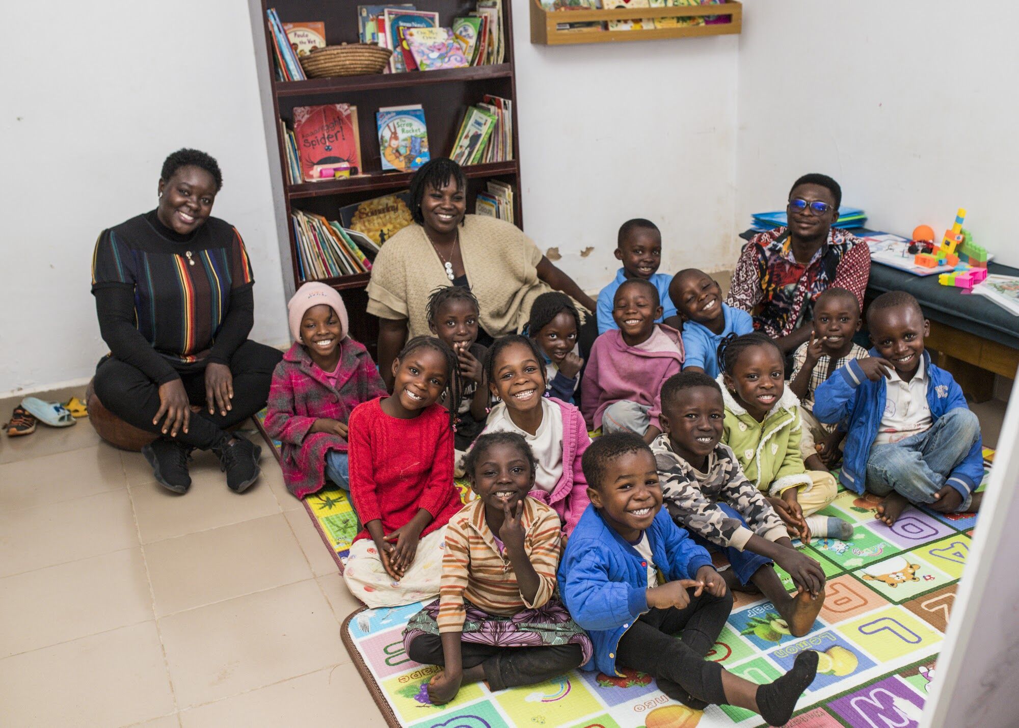 Young learners and their teachers smiling together in a community learning centre