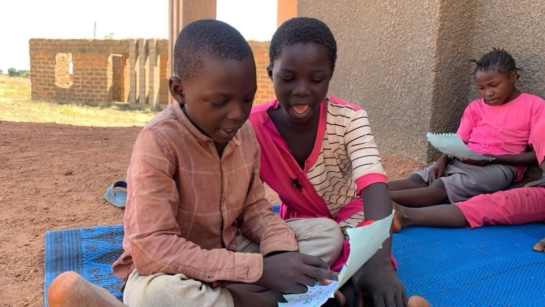 Children reading together outdoors