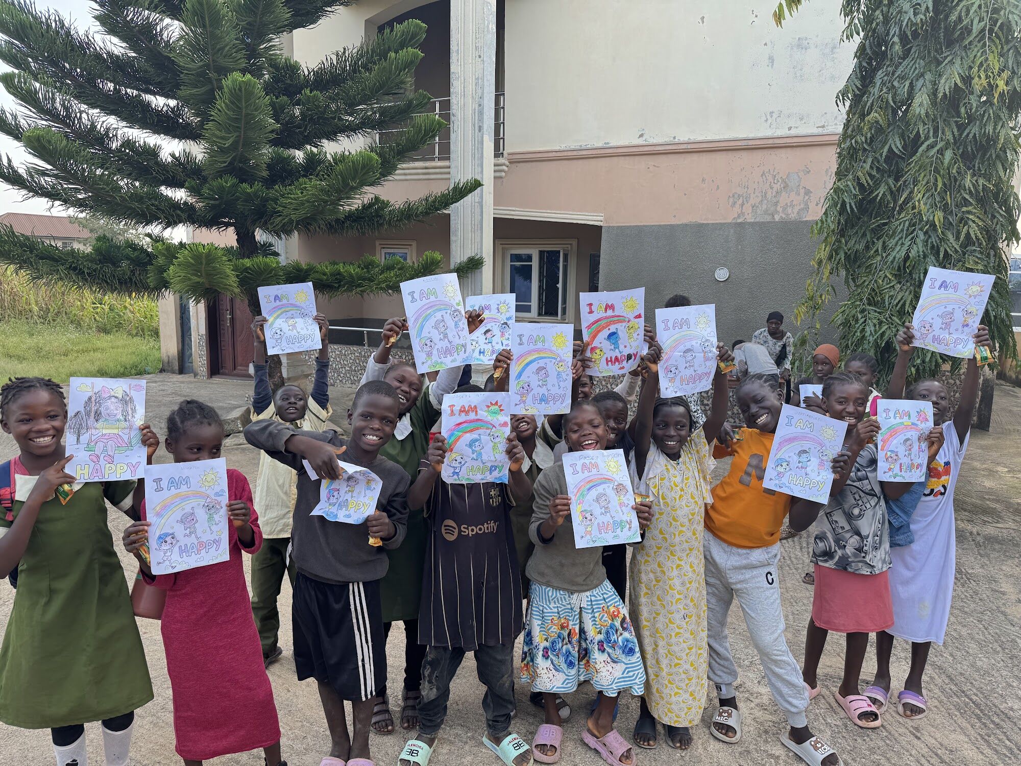 Learners holding up their "I am happy" drawings