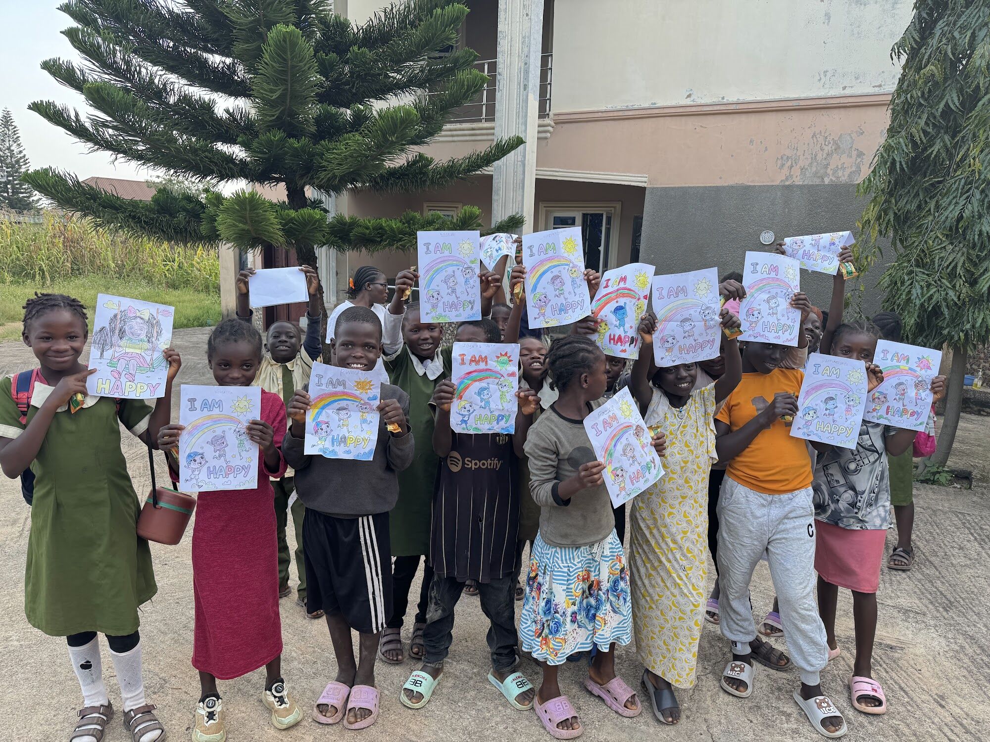 Learners smiling and holding up their drawings