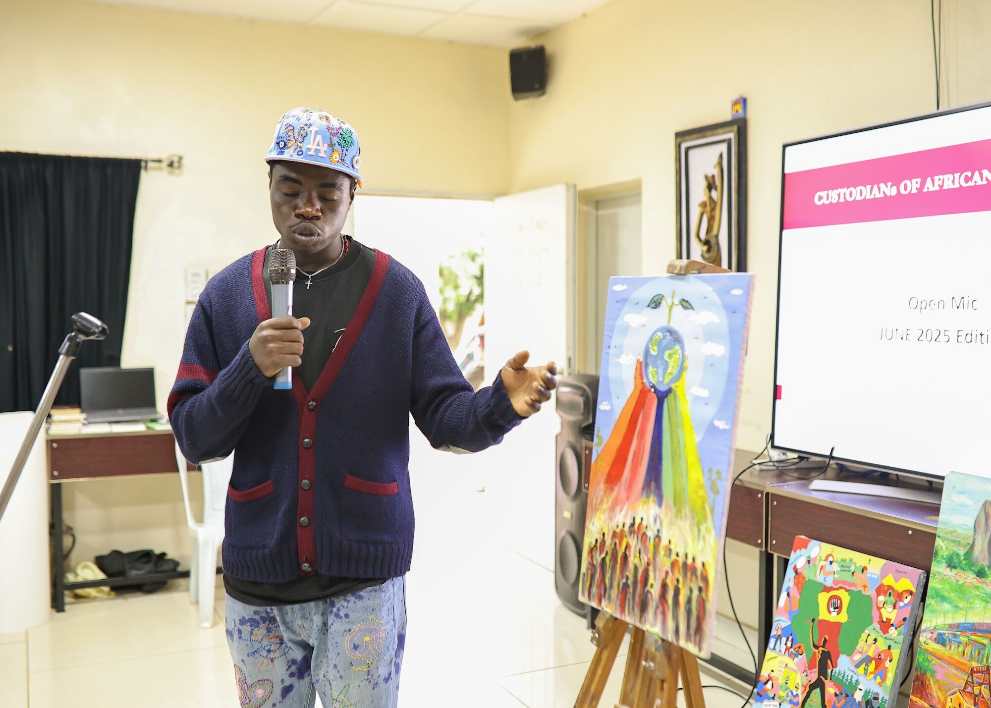 A performer beside his painting at a COAL Open Mic