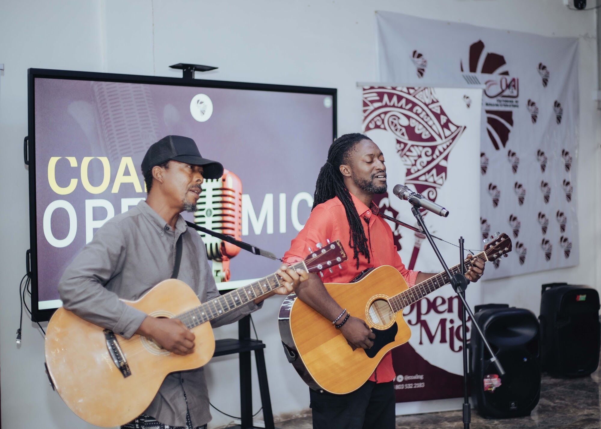 Two musicians playing guitar on the COAL Open Mic stage
